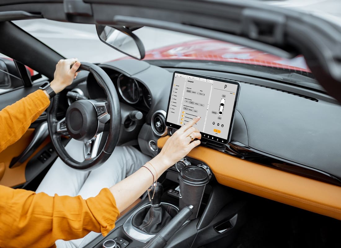 Telematics Insurance - Woman Controlling Her Car With a Digital Tablet and Switching to Autopilot While Driving on a Sunny Day